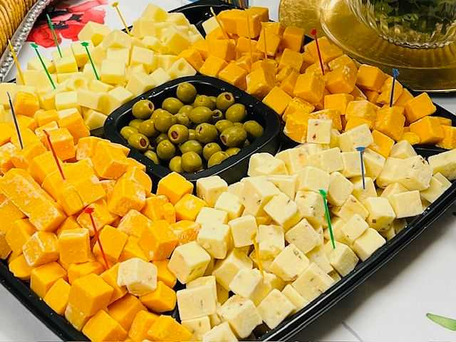 Platter with assorted cheese cubes and olives with toothpicks.